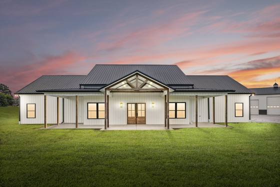 Main home at dusk — timber-truss entry and full-width covered porch