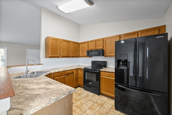 Kitchen with granite counters, subway tile backsplash and black appliances