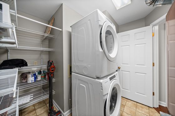 Laundry closet with stacked washer and dryer and wire shelving