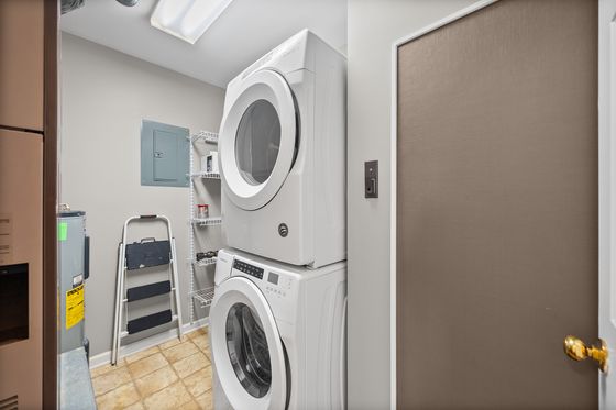 Utility closet with stacked laundry, water heater and electrical panel