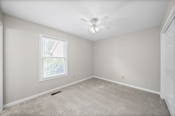 Carpeted bedroom with window and ceiling fan
