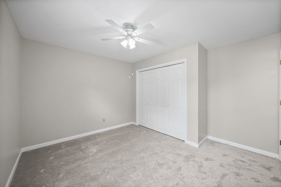 Carpeted bedroom with closet and ceiling fan