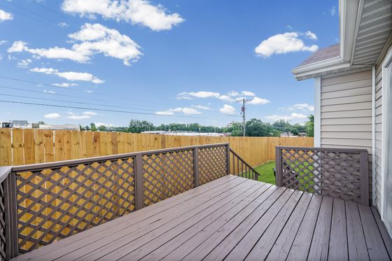 Wood deck off the back of the home overlooking a fenced yard